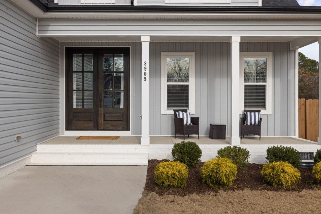 Inviting front porch with chairs and shrubs, perfect for relaxation.